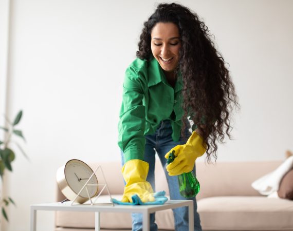 Happy Cleaner Lady Cleaning And Dusting Table At Home
