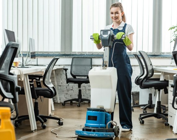 smiling cleaner washing floor in office with cleaning machine